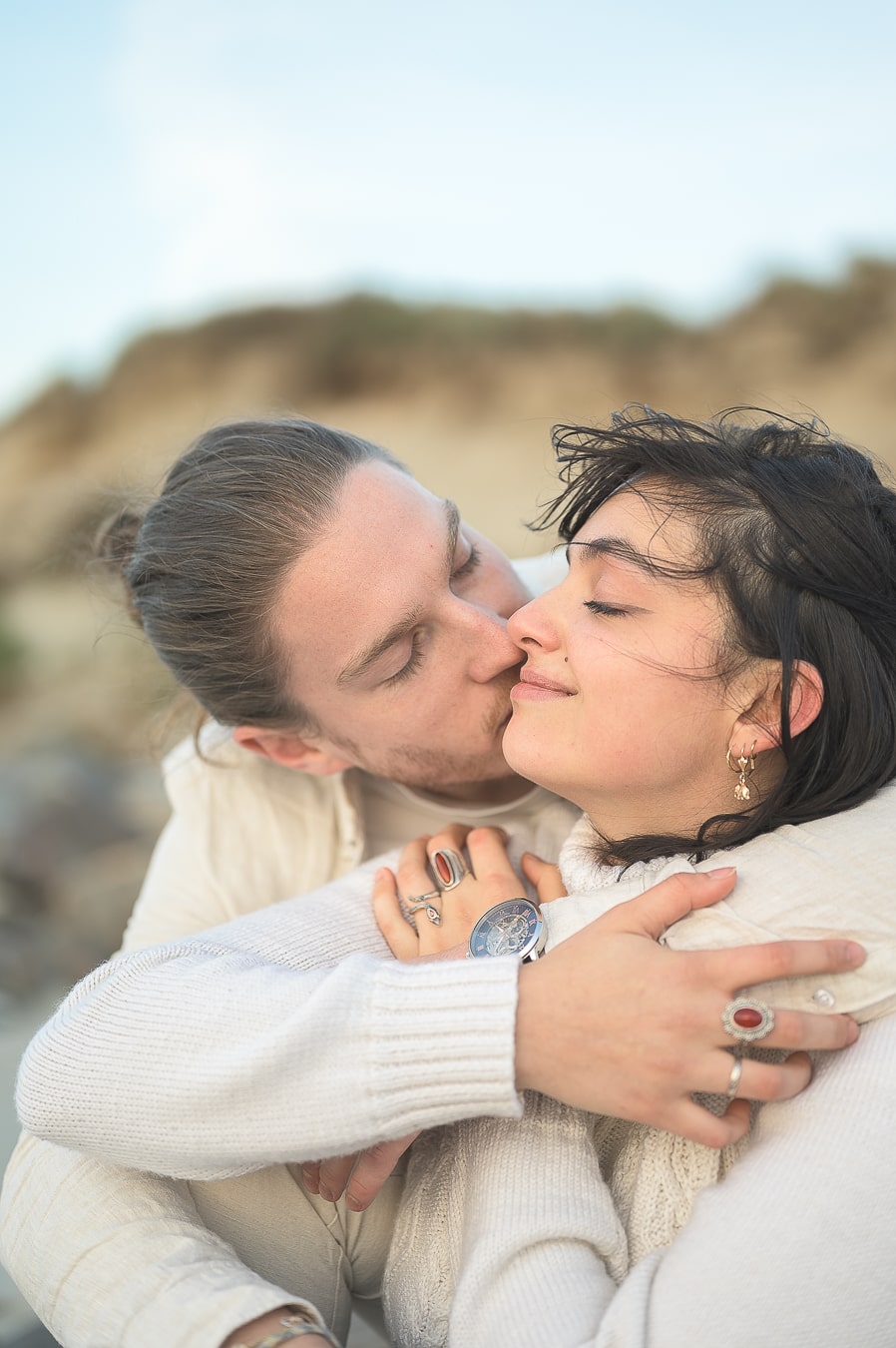 Séance photo de couple en bord de mer en Bretagne, un moment de tendresse capturé au coucher du soleil pour immortaliser leur amour naturel et sincère.