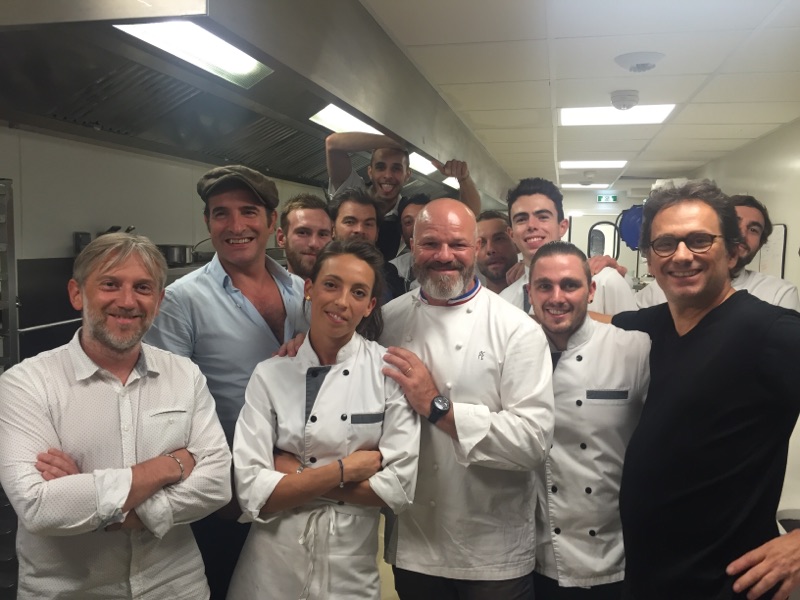 Photo souvenir en cuisine avec le chef Philippe Etchebest et l’acteur Jean Dujardin, entourés de la brigade dans un restaurant gastronomique.