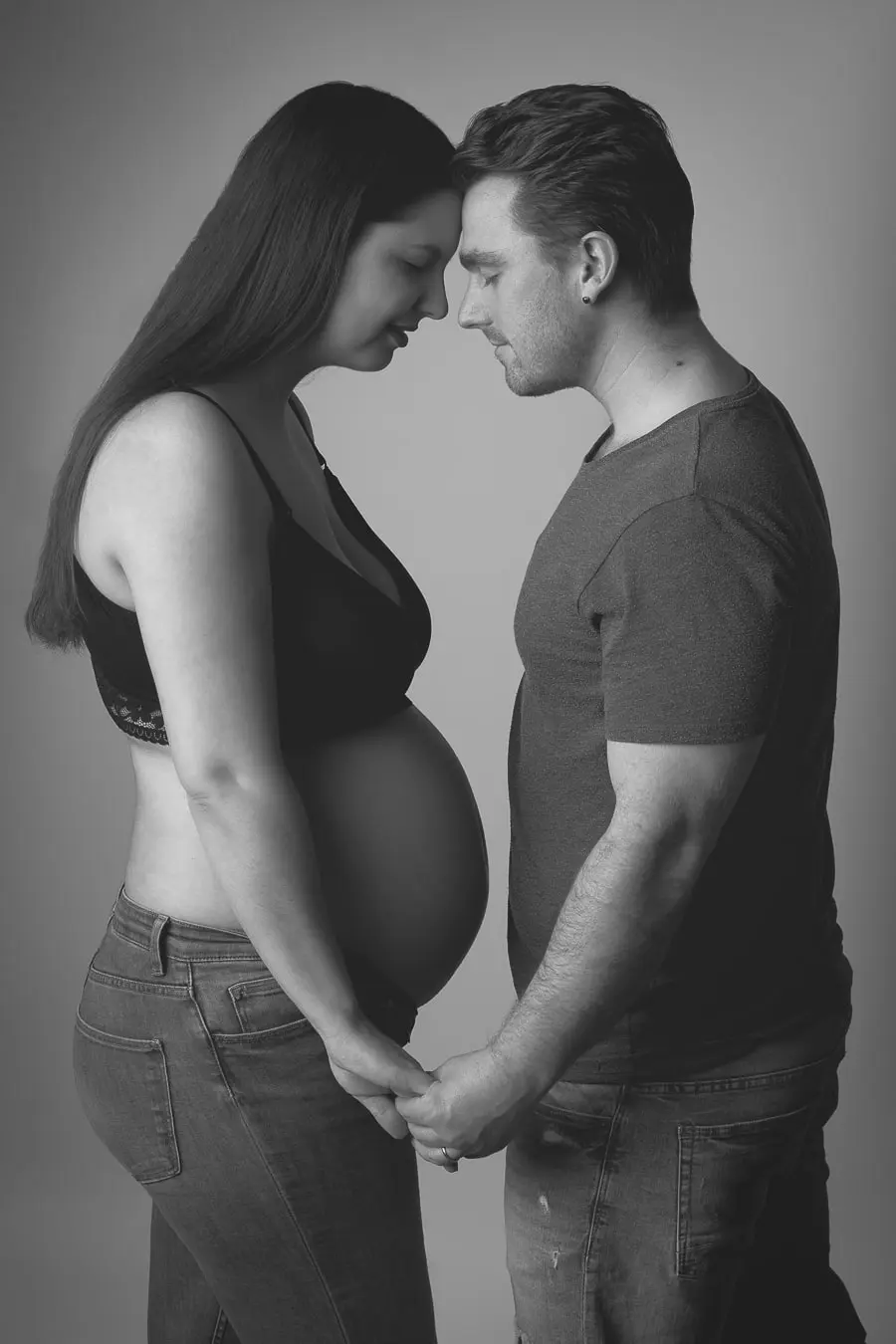 Portrait en studio d’un couple attendant un bébé, capturant un moment de complicité et d’émotion avant l’arrivée de leur enfant.