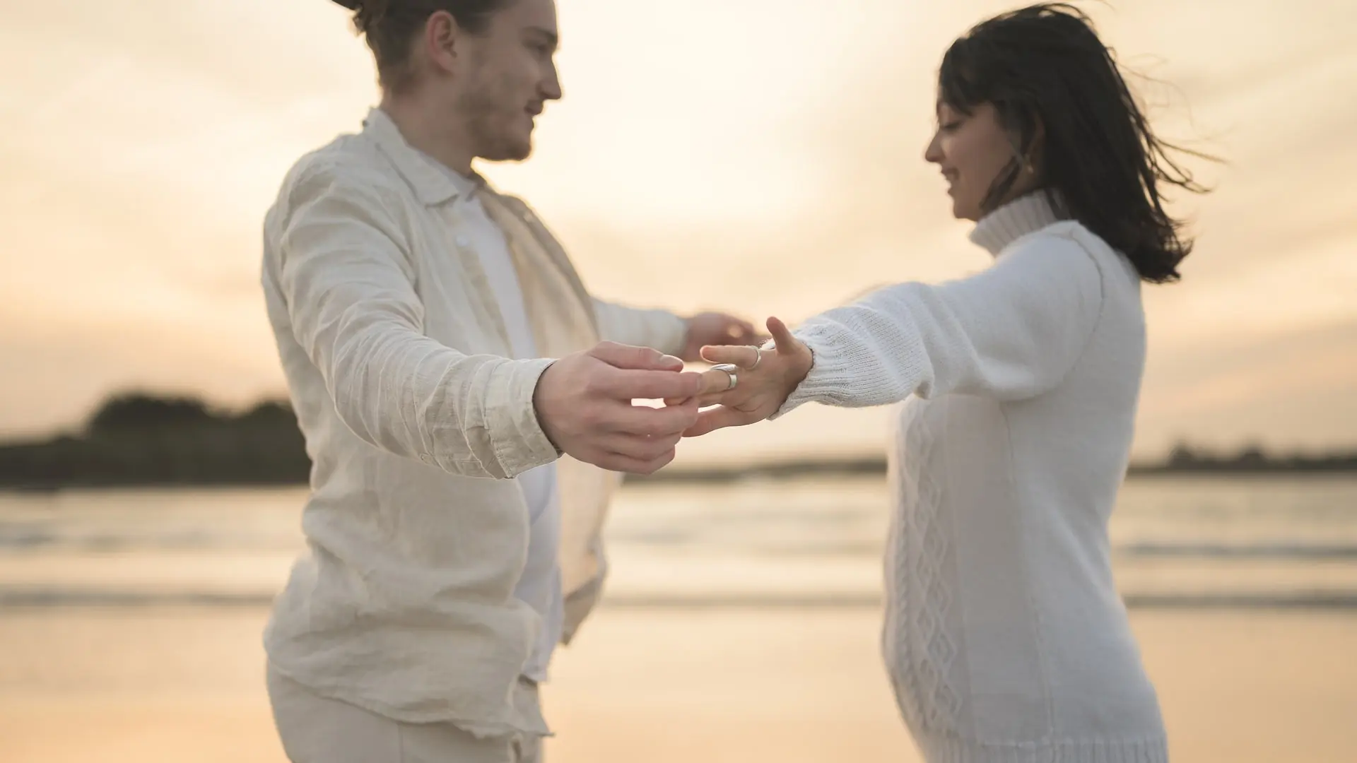 couple-complice-se-tenant-les-mains-au-bord-de-l-eau-au-coucher-du-soleil