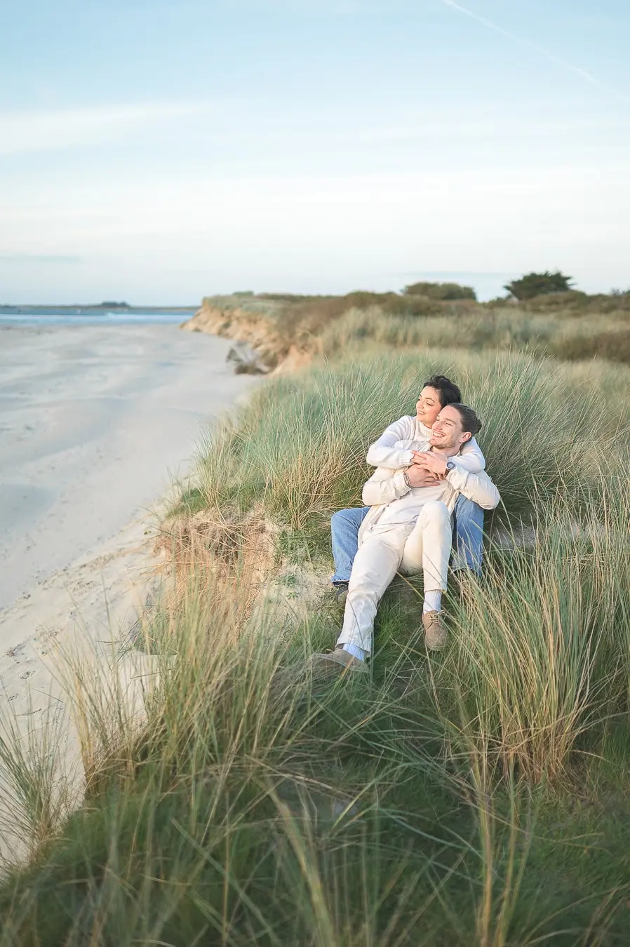 couple-assis-dans-les-dunes-enlacé-en-surplombant-la-plage-en-bretagne