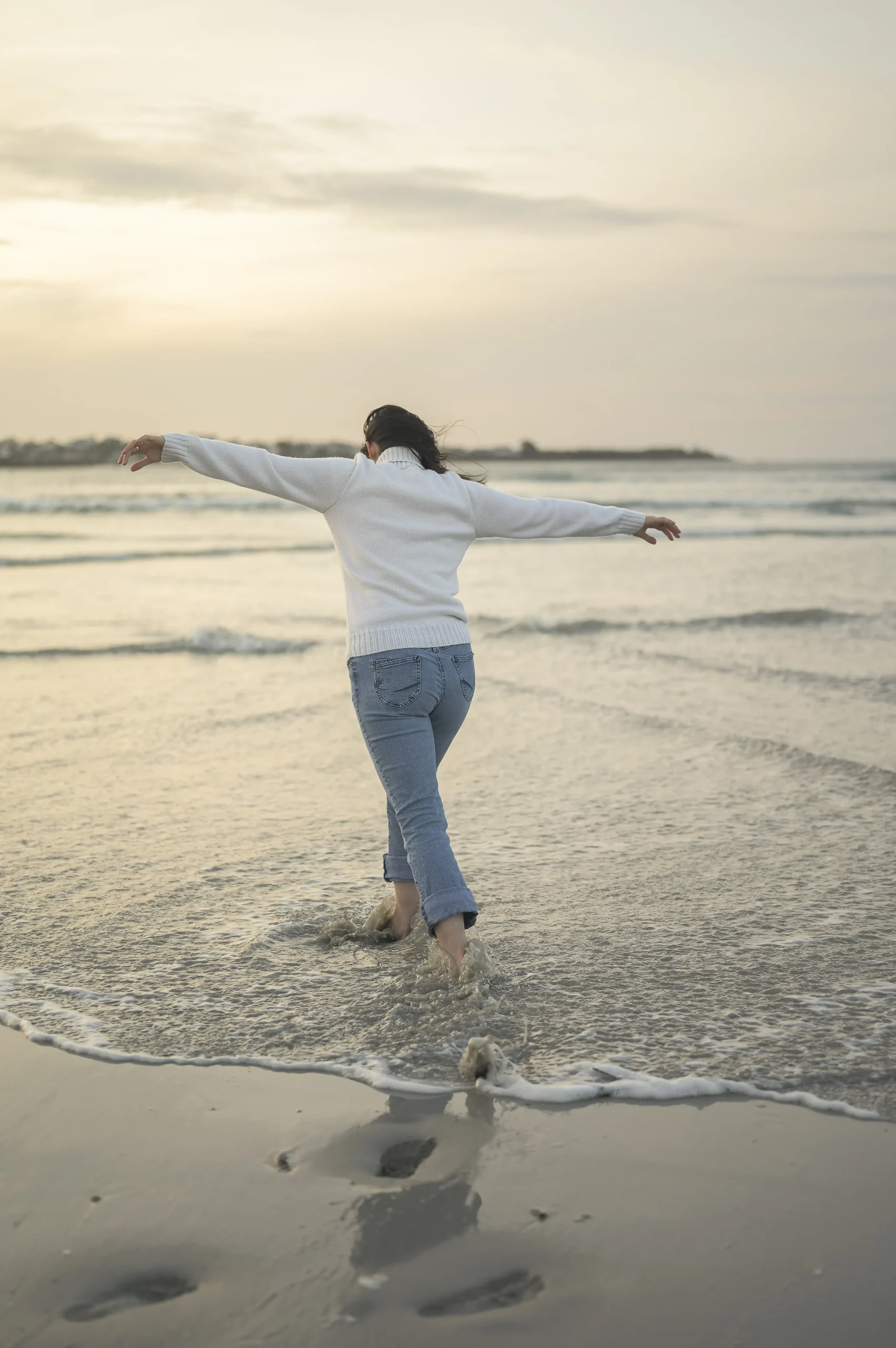 Jeune-femme-avançant-pieds-nus-dans-les-vagues-en-fin-de-journée-sur-la-plage-en-Finistère