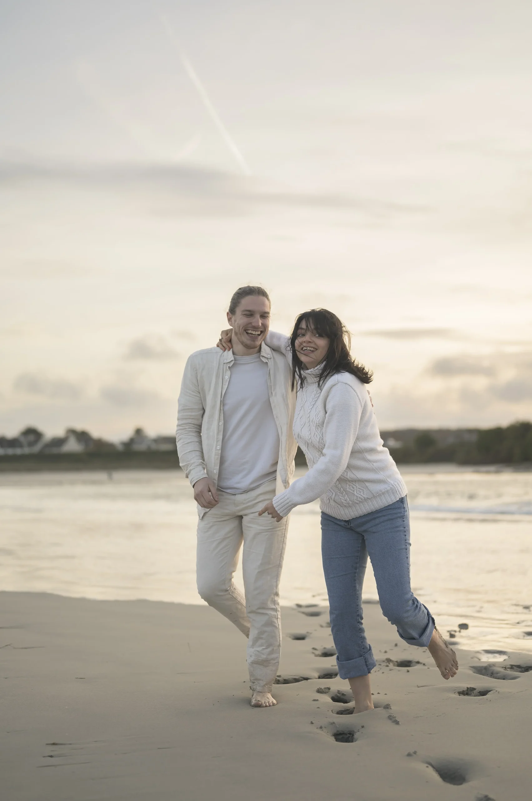 Fous rires d’un couple complice sur une plage en Bretagne au coucher du soleil