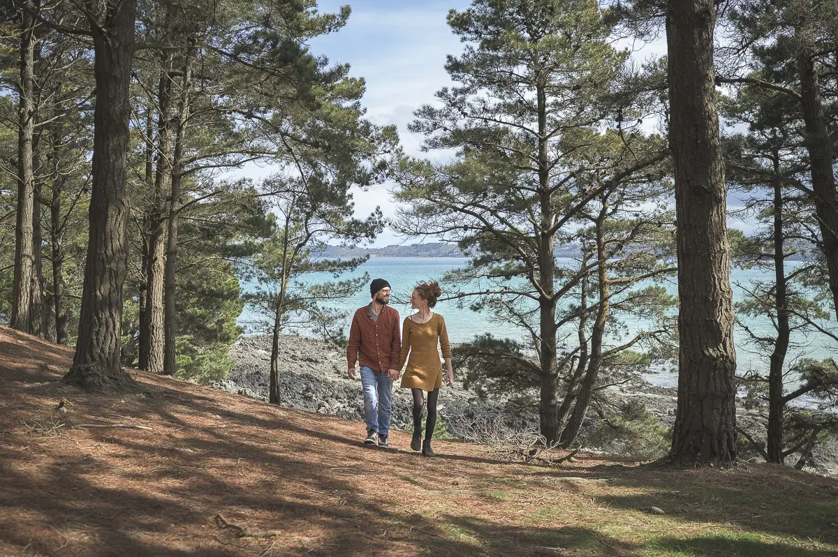 marche main dans la main forêt de pins lumière douce mer en arrière-plan justine etienne regard complice