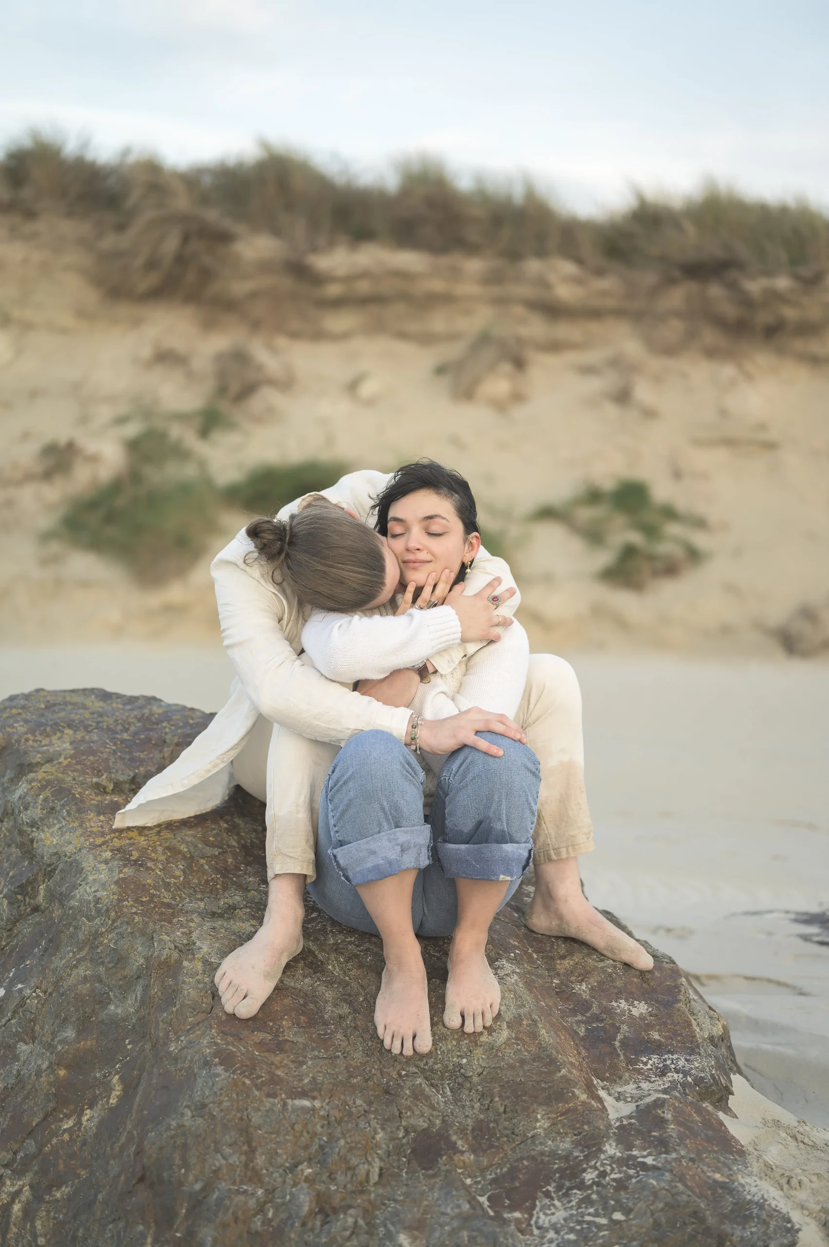 Couple-enlacé-sur-un-rocher-au-bord-de-la-plage-en-Bretagne-dans-un-moment-de-douceur