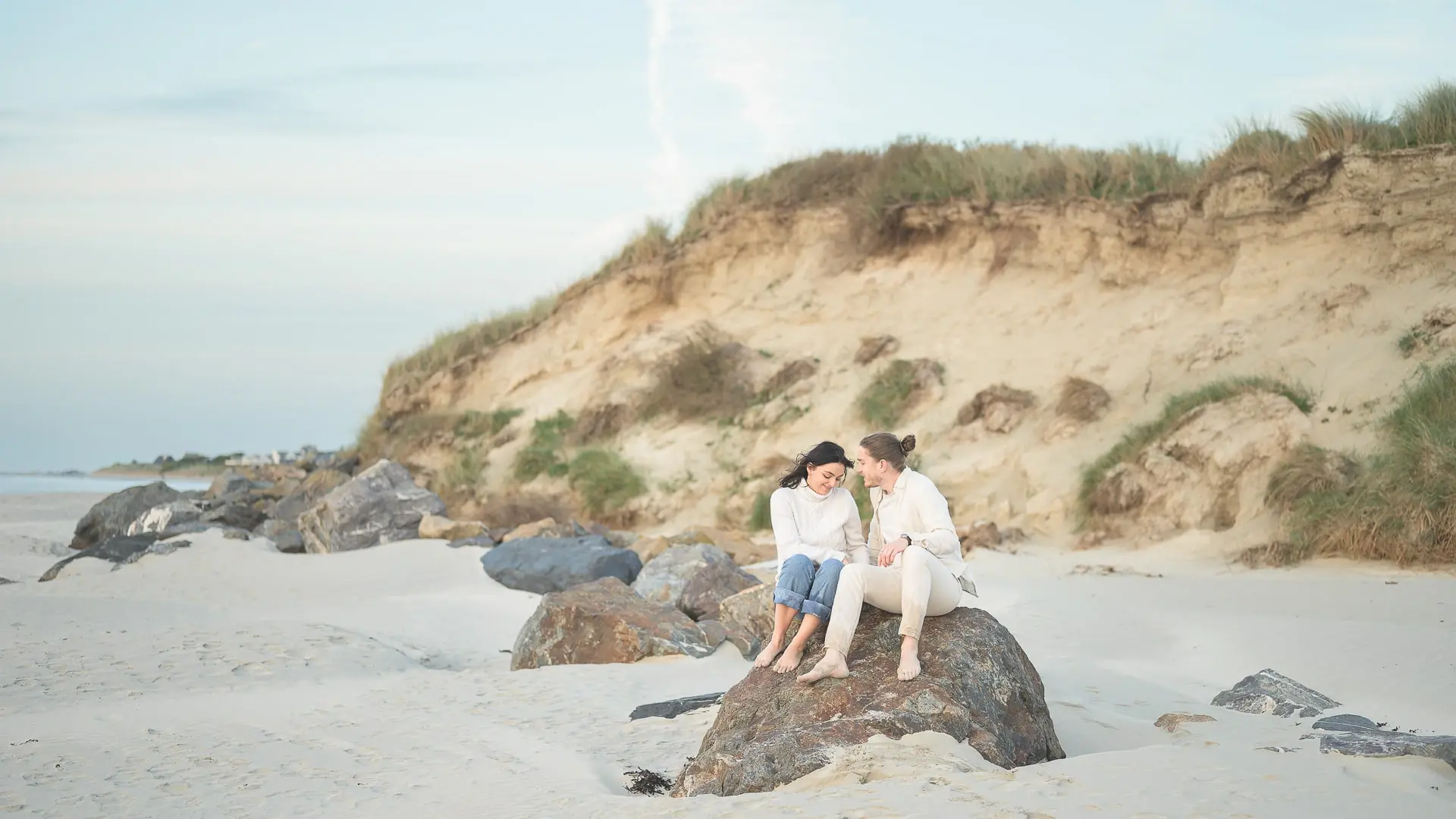 Couple-assis-sur-les-rochers-d-une-plage-en-Bretagne-lors-d-une-séance-photo-de-fiançailles