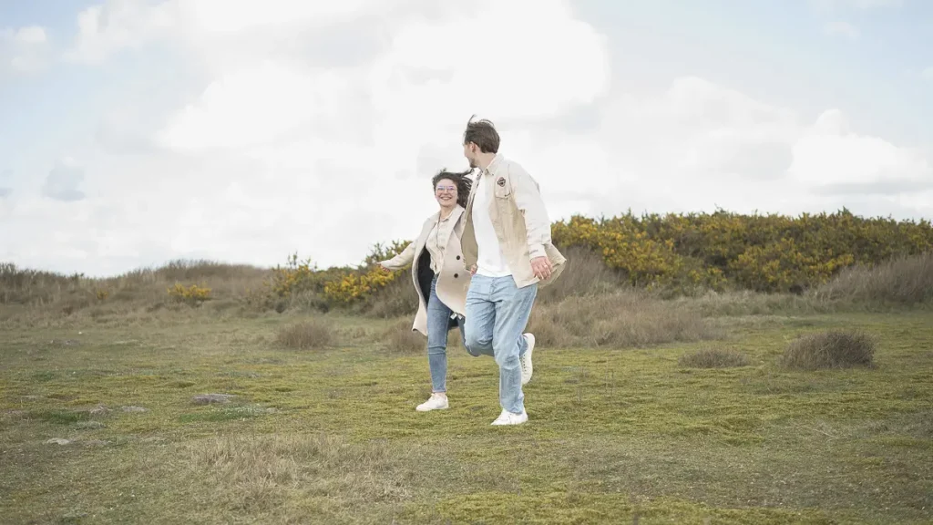 couple-qui-court-dans-les-dunes-sourire-aux-levres-lumiere-bretonne